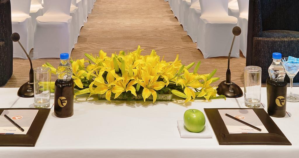 فندق ويلكوم هوتل بنجالور بنغالور المظهر الخارجي الصورة A table with a microphone, a bottle of water, a green apple and a flower arrangement